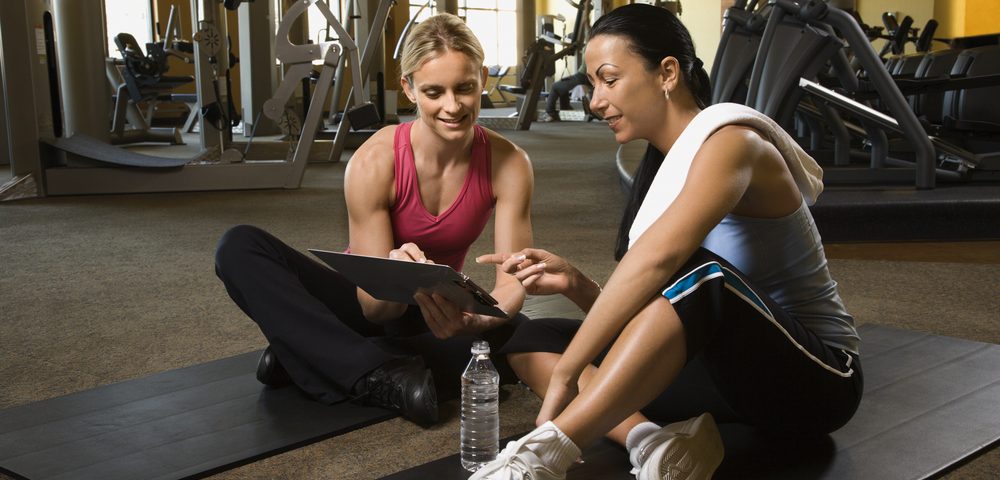 a personal trainer sitting with a client explaining how well they did in their session.